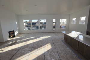 Unfurnished living room featuring plenty of natural light and a glass covered fireplace