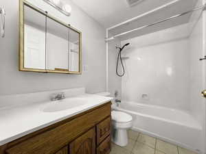 Bathroom featuring bathtub / shower combination, vanity, light tile patterned floors, and a textured ceiling