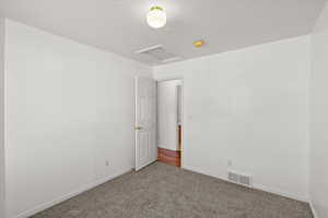 Carpeted empty room featuring attic access and baseboards
