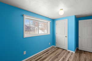 Unfurnished bedroom with a textured ceiling, light wood-type flooring, and a closet