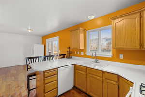 Kitchen with a breakfast bar, white appliances, a peninsula, and light countertops