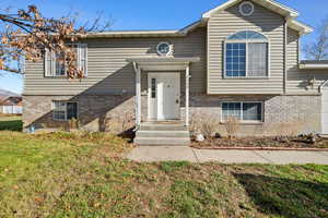 Split foyer home featuring brick siding and a front yard