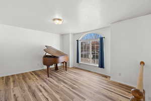 Empty room with light wood finished floors and a textured ceiling