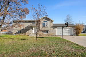 View of front of home with brick siding, concrete driveway, a front yard, and a garage