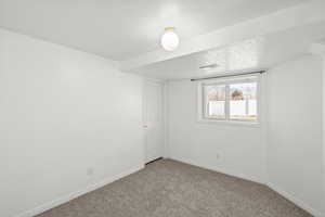 Carpeted spare room featuring a textured ceiling and baseboards