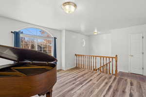Sitting room with an upstairs landing, wood finished floors, and a textured ceiling