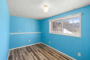 Empty room featuring a textured ceiling and wood finished floors