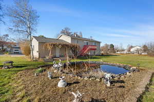 Rear view of house featuring a yard, stairway, and roof with shingles