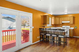 Kitchen with gas range gas stove, light countertops, a breakfast bar, dark wood-type flooring, and extractor fan