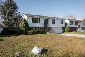 Bi-level home with brick siding, driveway, a front lawn and a 2-car attached garage
