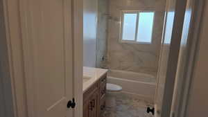 Main bath from hall with vanity, light marble finish flooring & shower / tub combination