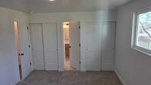 Primary bedroom with two closets, carpet flooring and separate connection to main bath