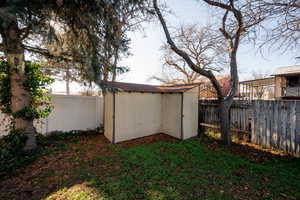 Fenced backyard featuring a storage shed