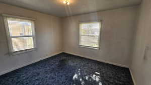 Bedroom 1 with dark colored carpet and baseboards