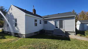 Back of property featuring entry steps, a yard, and roof with shingles