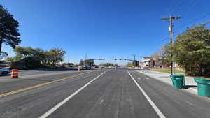 View of asphalt street featuring curbs, sidewalks and street