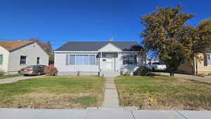 Bungalow featuring a front lawn and roof with shingles