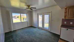 Unfurnished dining area with a ceiling fan and dark carpet