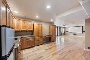 Kitchen with freestanding refrigerator, tasteful backsplash, light wood-type flooring, recessed lighting, and open floor plan