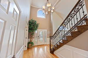Foyer entrance with wainscoting, a decorative wall, light wood finished floors, ornamental molding, and healthy amount of natural light