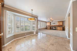 Unfurnished living room with ornamental molding, arched walkways, stone tile floors, a glass covered fireplace, and a ceiling fan