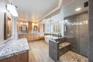 Full bathroom featuring ornamental molding, double vanity, a freestanding tub, a shower stall, and light wood-type flooring