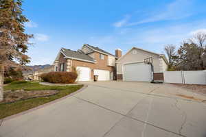 View of front of house featuring brick siding, concrete driveway, a garage, a gate, and a chimney