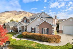 View of front of property featuring brick siding, a chimney, stucco siding, a garage, and a mountain view