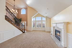 Unfurnished living room with a decorative wall, a wainscoted wall, a chandelier, a premium fireplace, and healthy amount of natural light