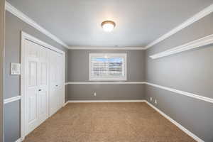 Unfurnished bedroom featuring light colored carpet, a closet, and crown molding