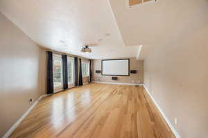 Home theater featuring light wood finished floors and a textured ceiling