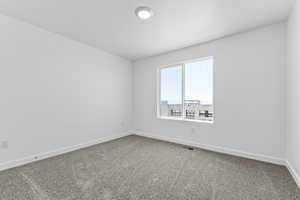 Carpeted spare room featuring baseboards