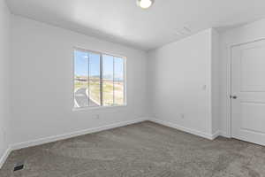 Carpeted spare room featuring baseboards