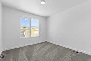 Carpeted spare room featuring baseboards