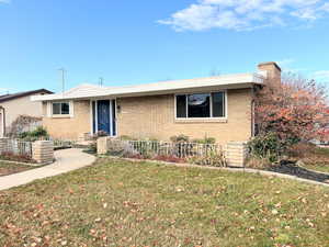 Ranch-style house with a front lawn, brick siding, and a chimney