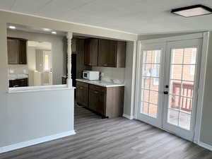 Kitchen featuring dark brown cabinets, light countertops, white microwave, and dark wood-type flooring