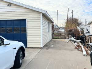 View of side of home featuring a patio, a garage, and an outbuilding
