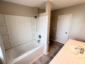 Bathroom featuring vanity, shower / bathtub combination, and dark wood finished floors