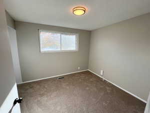 Carpeted spare room featuring baseboards