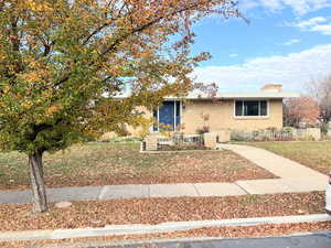 View of front facade with brick siding, a chimney, and a front lawn