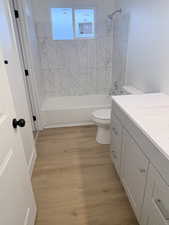 Full bathroom with light wood-type flooring, vanity, and tub / shower combination