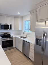 Kitchen featuring stainless steel appliances, light wood finished floors, recessed lighting, light stone counters, and white cabinetry