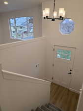 Entrance foyer featuring stairway, wood finished floors, a chandelier, and a towering ceiling