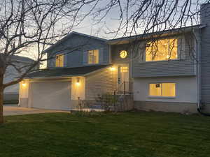 View of front of house with a garage, a front lawn, and driveway