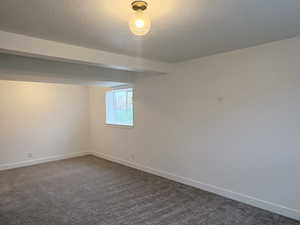 Empty room featuring dark carpet and a textured ceiling