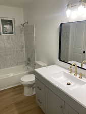 Bathroom featuring vanity, shower / washtub combination, and dark wood-style floors