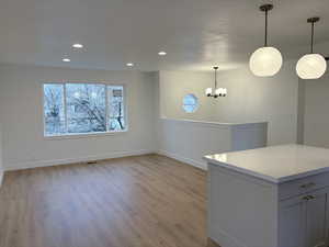 Unfurnished dining area with light wood-style flooring, recessed lighting, and a chandelier