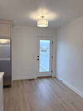 Doorway to outside with wood finished floors and a textured ceiling