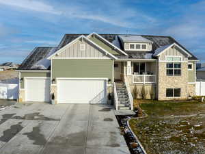 Craftsman-style home featuring stone siding, board and batten siding, concrete driveway, and a garage