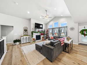 Living room featuring a fireplace, light wood-type flooring, ceiling fan, recessed lighting, and high vaulted ceiling